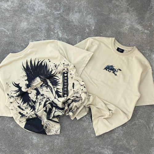 Beige streetwear t-shirts with anime samurai graphic and sword design, laid on concrete