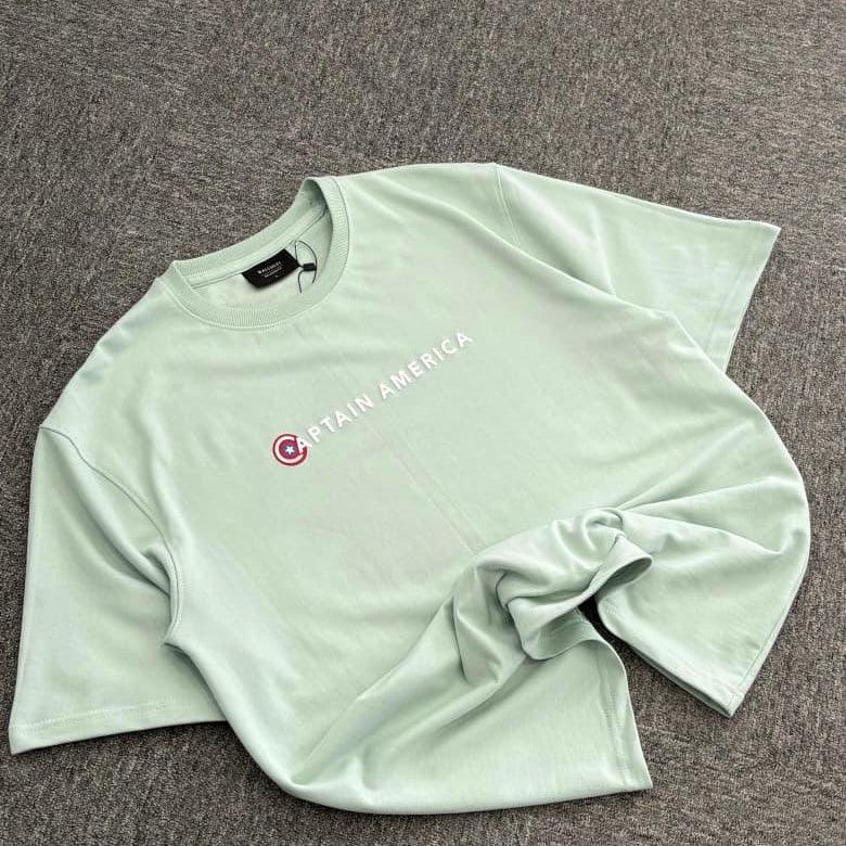 Light green Captain America graphic t-shirt laid flat on a gray surface