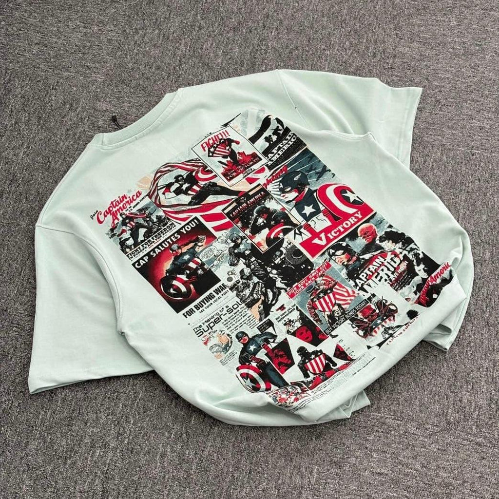 Light grey T-shirt with vintage comic collage graphic design on the back, laid on carpet