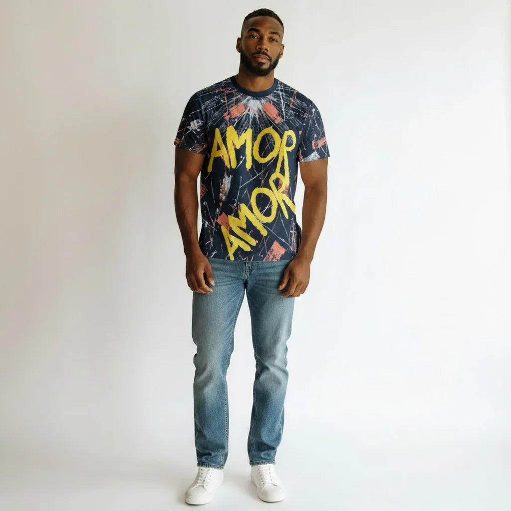 Man wearing graphic t-shirt with 'AMOR' text, blue jeans, and white sneakers on white background