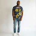 Man wearing graphic t-shirt with 'AMOR' text, blue jeans, and white sneakers on white background