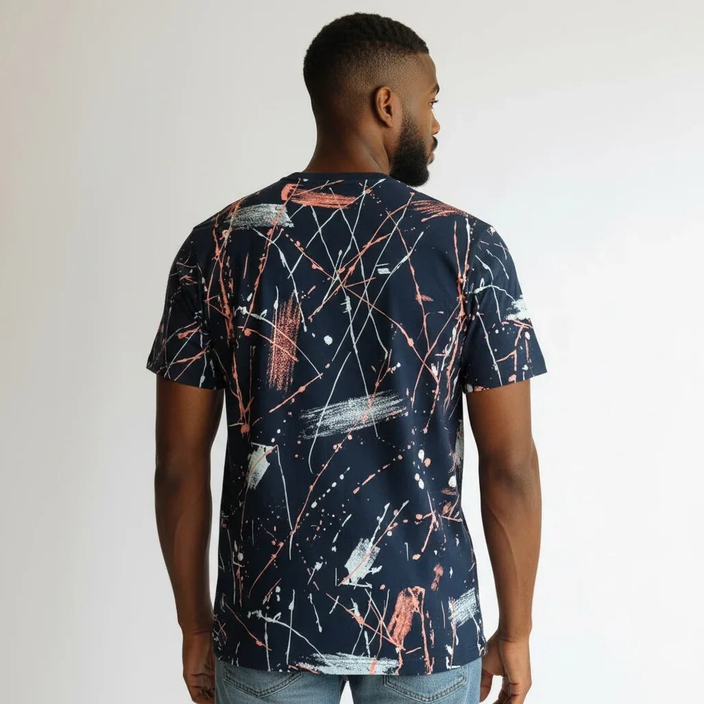Man wearing navy t-shirt with abstract paint splatter design, shown from the back