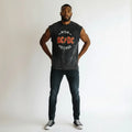 Man wearing sleeveless black AC/DC graphic t-shirt, black jeans, and sneakers on white background
