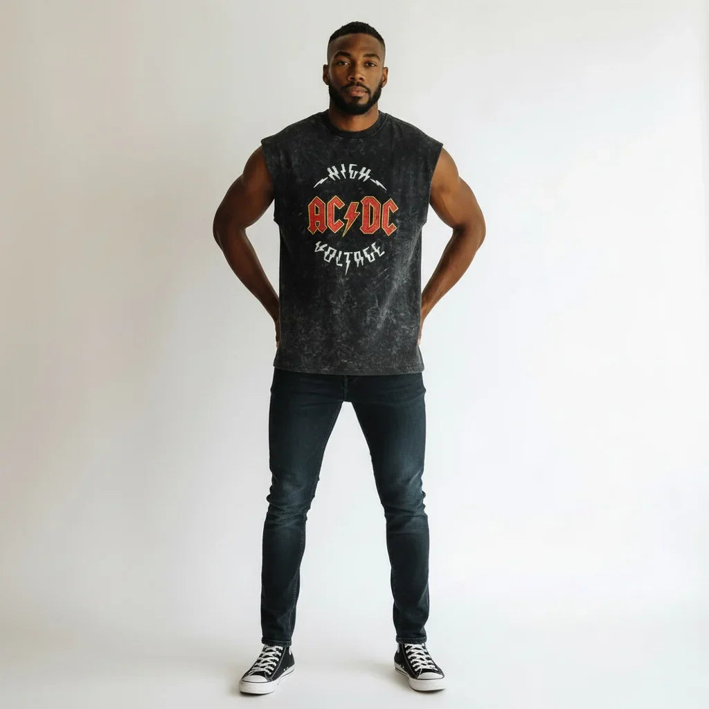 Man wearing sleeveless black AC/DC graphic t-shirt, black jeans, and sneakers on white background