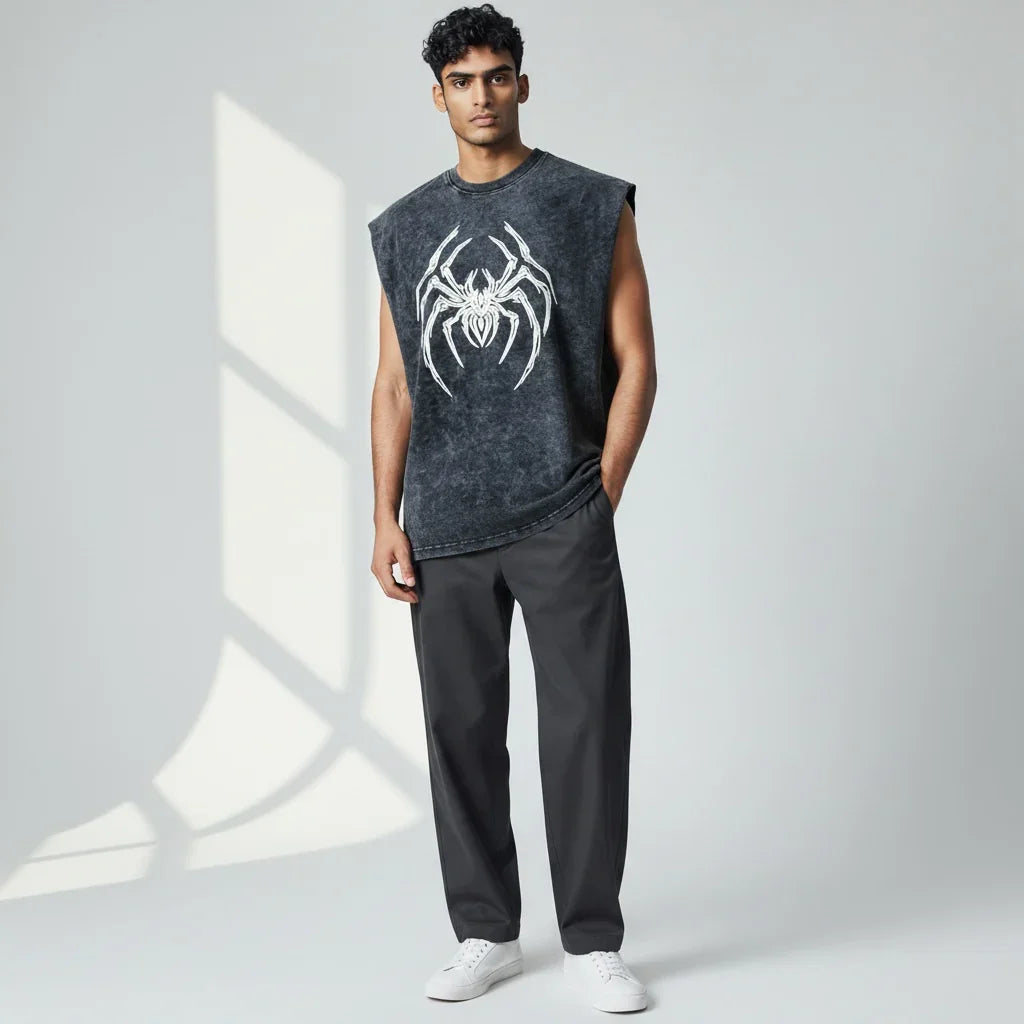 Man wearing sleeveless black shirt with bold white spider graphic, gray pants, and white sneakers