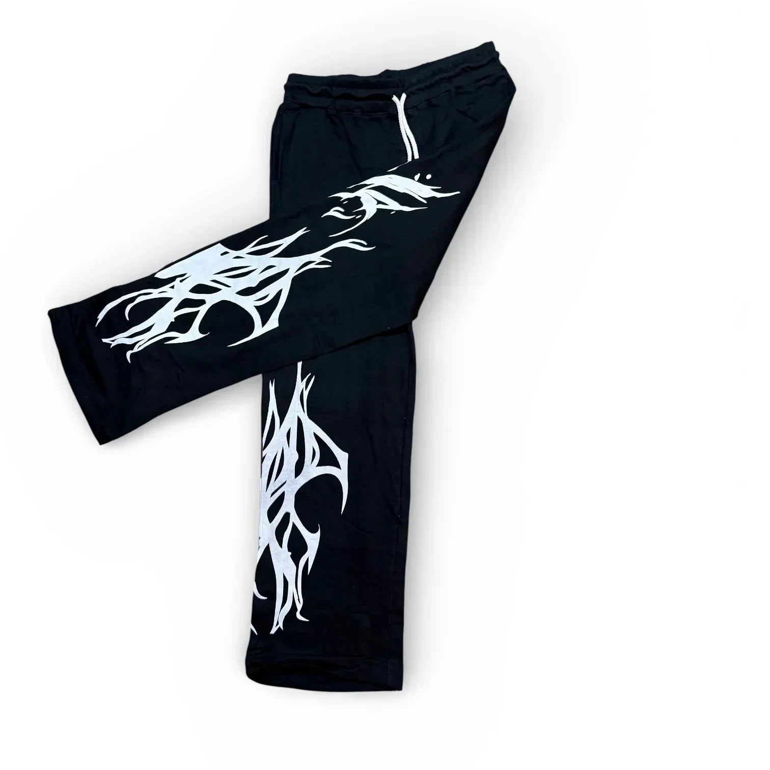 Black streetwear pants with bold white tribal graphic print, flat lay on white background