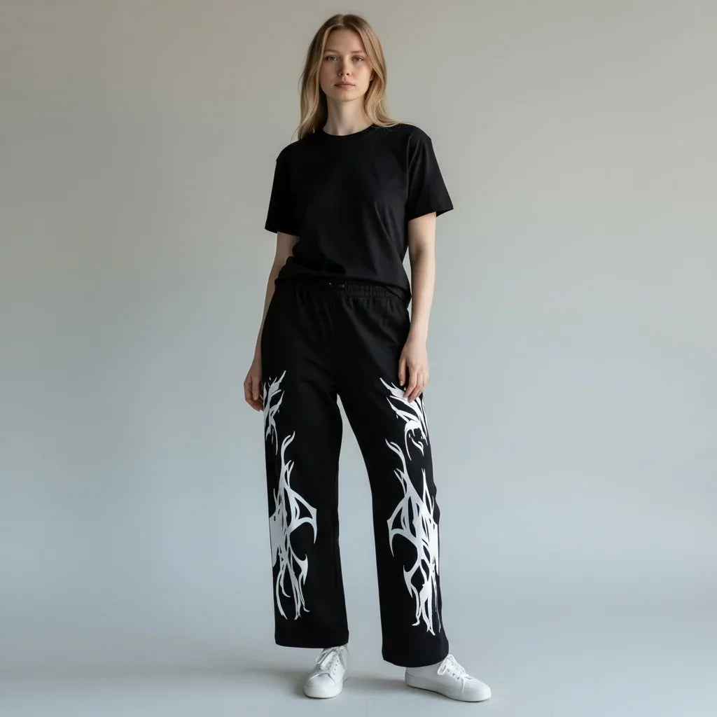 Woman wearing black t-shirt and black pants with white tribal flame graphic, white sneakers