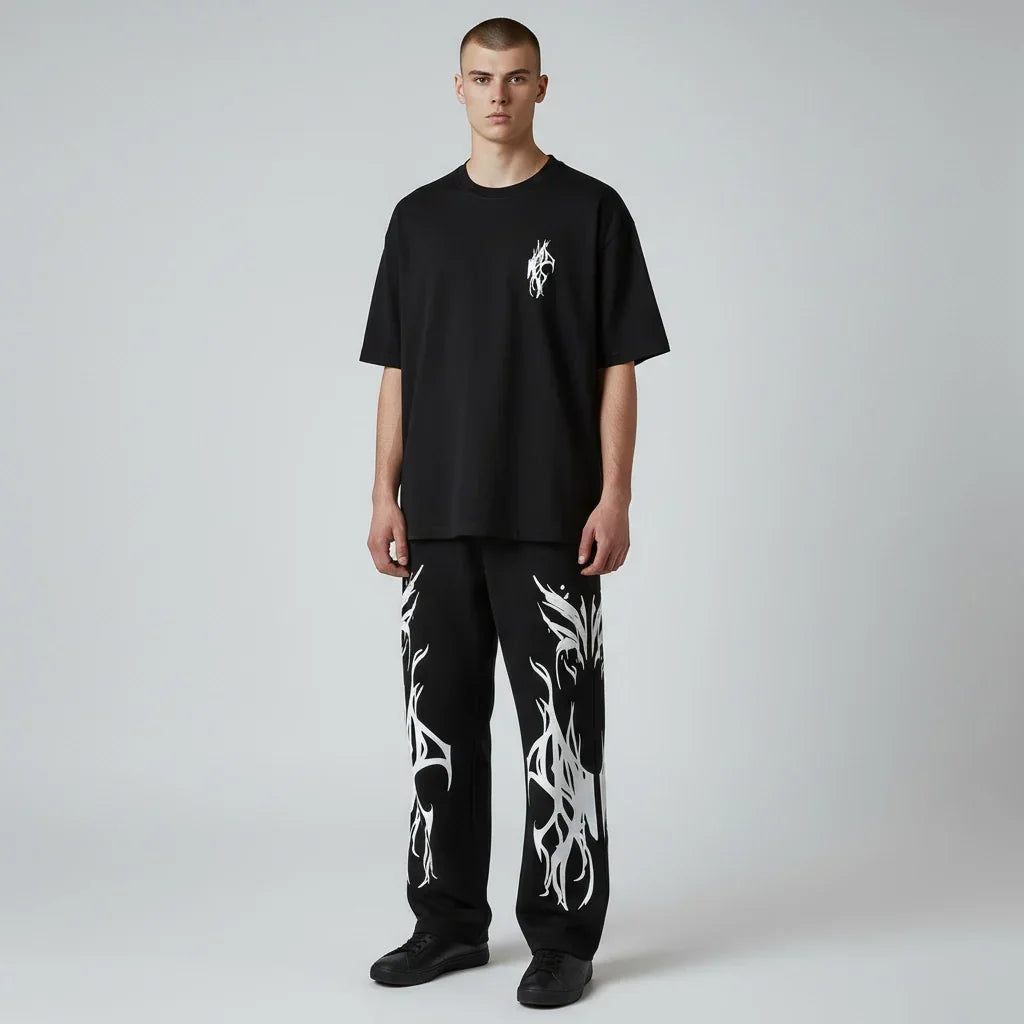 Man wearing black oversized t-shirt with white graphic and black pants with white flame design