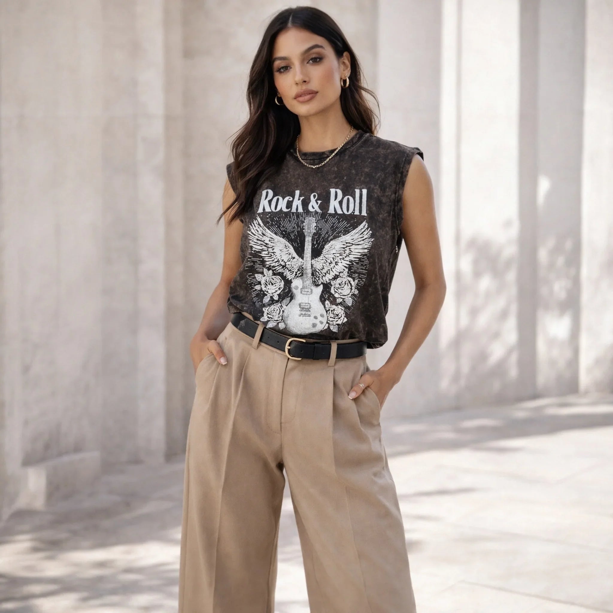 Woman wearing a black Rock & Roll graphic tee with guitar print and beige high-waisted pants.