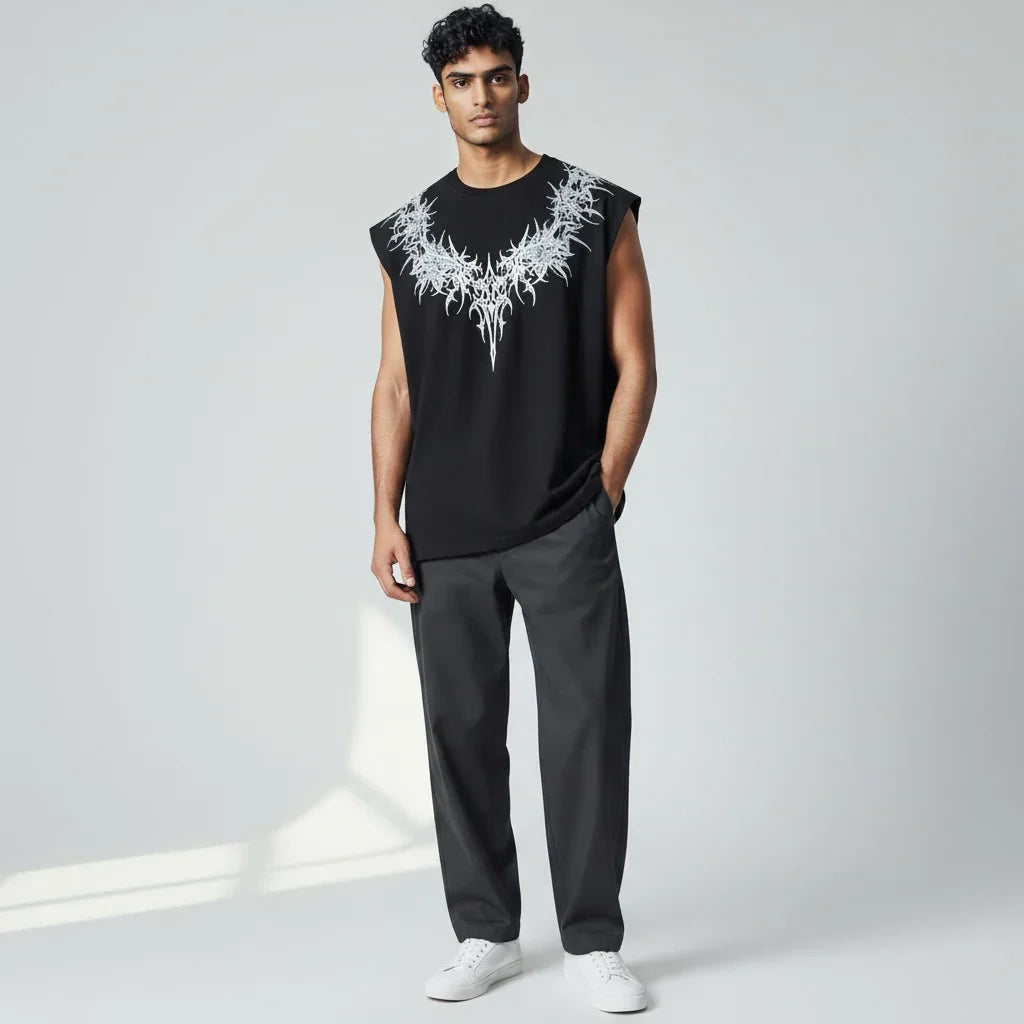 Man wearing black sleeveless graphic tee with abstract white design, gray pants, white sneakers