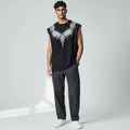 Man wearing black sleeveless graphic tee with abstract white design, gray pants, white sneakers