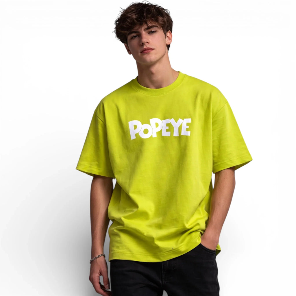 Man wearing lime green oversized POPEYE graphic T-shirt with black pants
